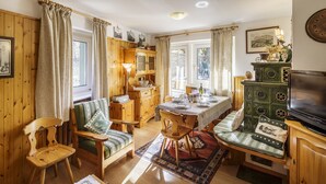 A cozy, well-lit room with wooden furniture, a dining table set for four, and a television on a cabinet.