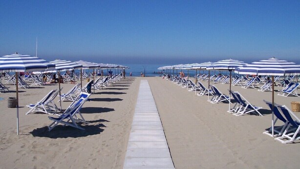 A beach with rows of sun loungers and umbrellas, a clear sky, and a walkway leading to the water. - Villa with private swimming pool, garden & sea view Forte Dei Marmi   (Pietrasanta)