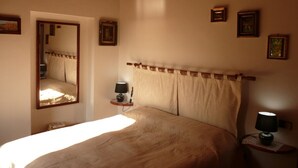 A bedroom with a large bed, a bedside table with a lamp, a mirror, and framed pictures on the wall. - Villa with private swimming pool, garden & sea view Forte Dei Marmi   (Pietrasanta)