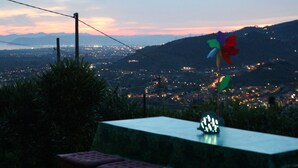 A table with a pinwheel and a glowing object on it, overlooking a cityscape at dusk with mountains in the background. - Villa with private swimming pool, garden & sea view Forte Dei Marmi   (Pietrasanta)