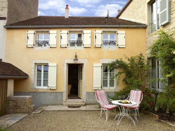 A two-story building with a yellow facade, white shutters, and a small entrance with steps.