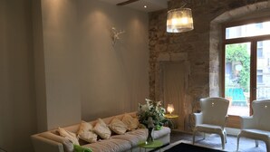 Un salon avec un canapé beige, une table d’appoint verte et une chaise blanche.