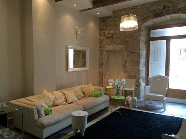 A living room with a sofa, a small round table, a chair, and a decorative wall piece.