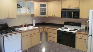 Une cuisine avec des meubles de rangement en bois, une cuisinière, un four, un four à micro-ondes et un lave-vaisselle.