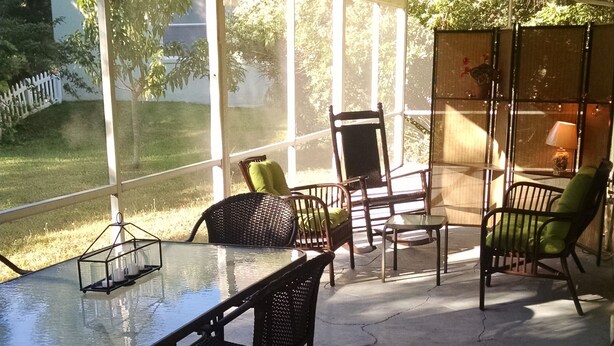 Une terrasse extérieure avec une table en verre et des chaises en osier.