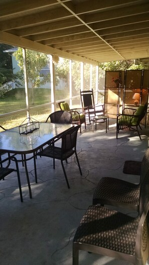Un patio esterno con un tavolo in vetro e sedie in vimini.