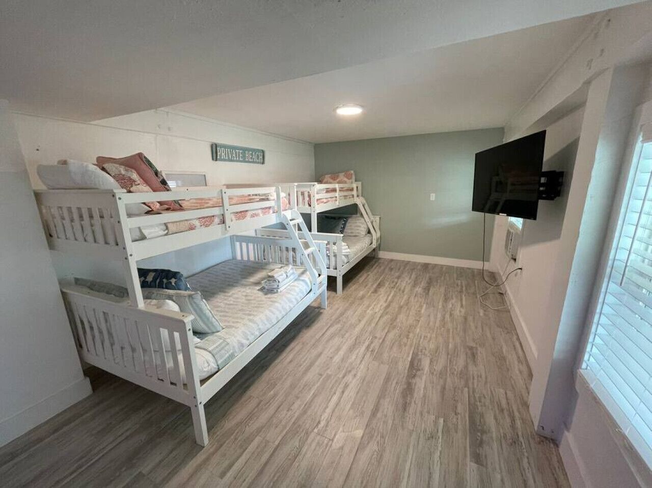 A room with bunk beds, a television, and a sign that reads "PRIVATE BEACH".