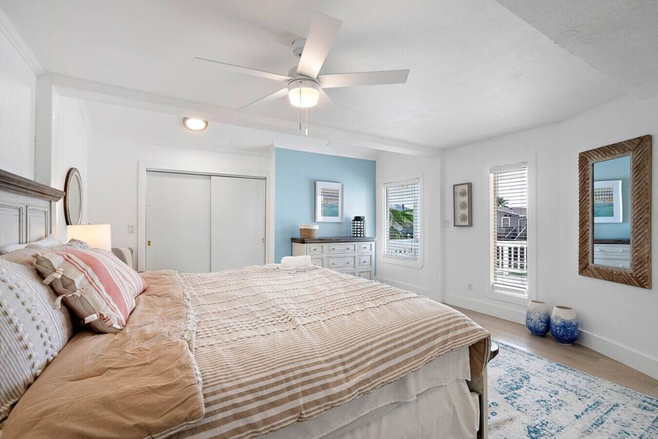 Un dormitorio con cama, ventilador de techo, cómoda, ventana con persianas y puerta.