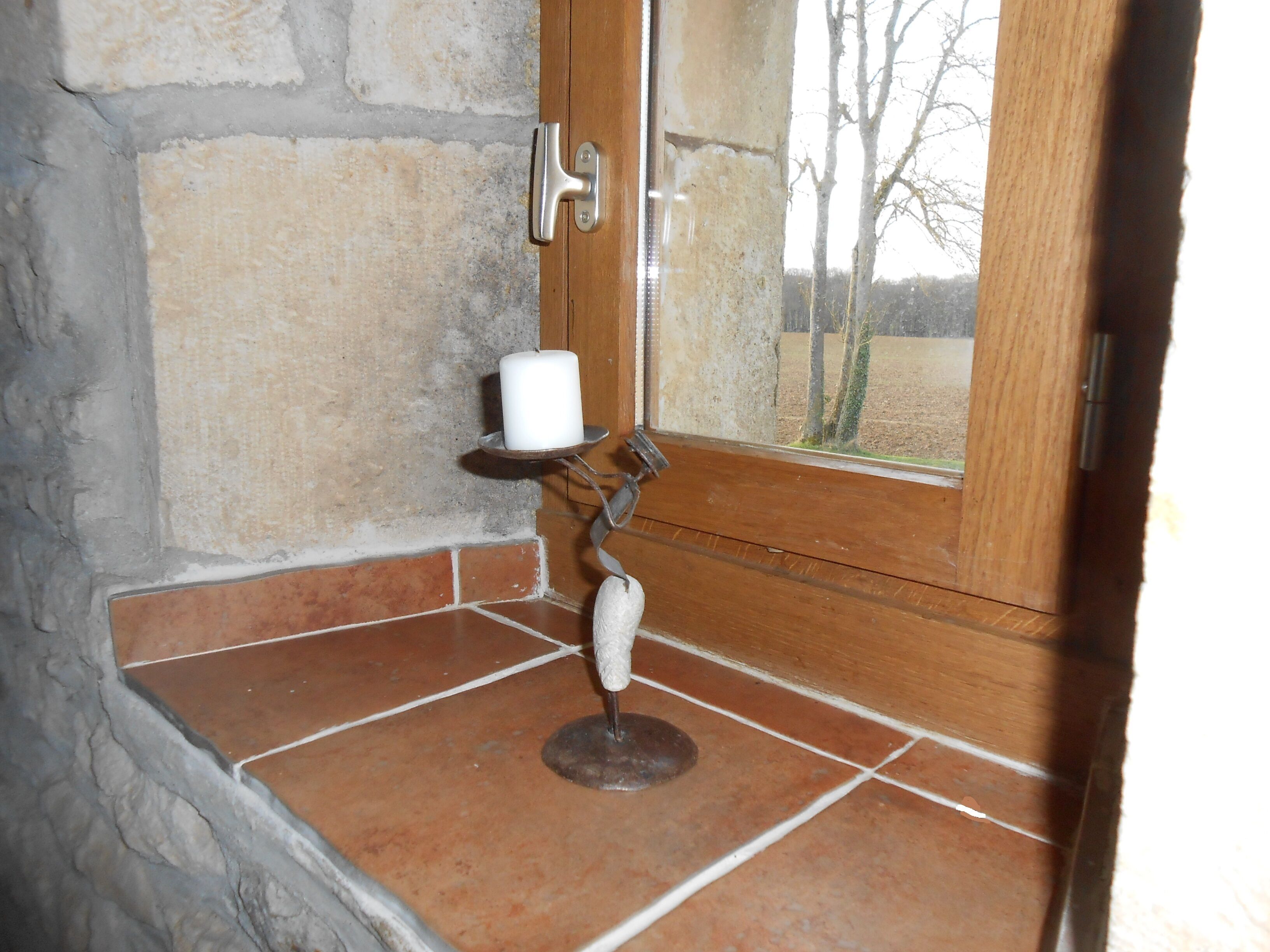 A corner of a room with a stone wall, a wooden door, and a tiled floor.