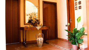 Un couloir avec une console en bois, un vase et une plante en pot.