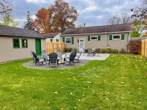 Une maison à deux étages dotée d’un patio aménagé avec du mobilier d’extérieur.