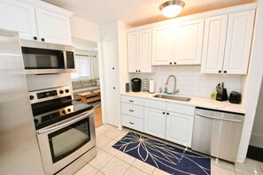 A compact kitchen with white cabinetry, a built-in oven, a microwave, and a sink.
