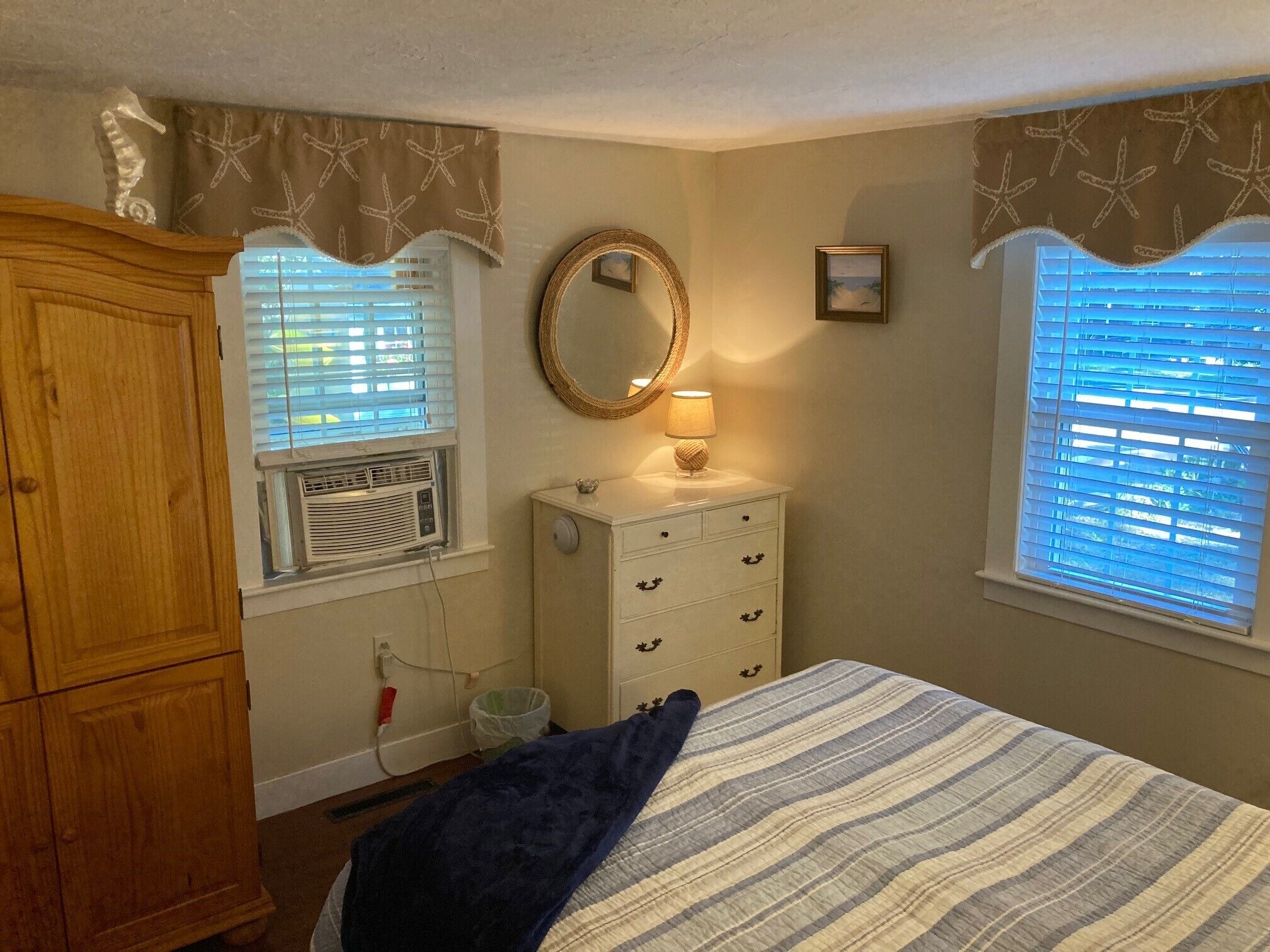 A bedroom with a bed, dresser, vanity, and a window with blinds.