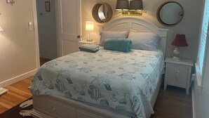Ein Schlafzimmer mit einem Bett, zwei Nachttischlampen, einem Nachttisch, einem Spiegel und einer Tür.