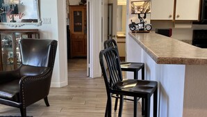 Una cocina moderna con barra, suelo de madera y zona de comedor con sillas.