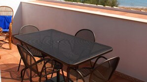 Une terrasse avec une table et des chaises, donnant sur une plage.