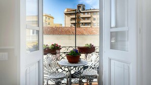 An open balcony with a table and chairs, potted plants, and a view of buildings in the background. - Cozy rooms to rent in Olbia City Center (Olbia)