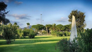 A well-maintained grassy area with a tall, narrow monument in the foreground, surrounded by various trees and shrubs. - Cozy rooms to rent in Olbia City Center (Olbia)