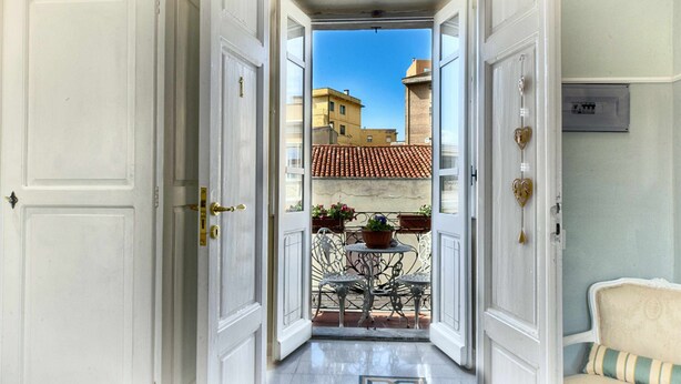 An open doorway leading to a balcony with a view of buildings and a tiled roof. - Cozy rooms to rent in Olbia City Center (Olbia)