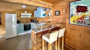 Una cocina con paredes de madera, un refrigerador, una estufa y una barra con taburetes.