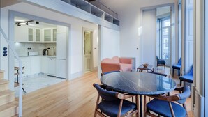 A modern loft apartment with a kitchen, dining area, and a staircase leading to a loft space.