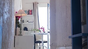 Un arco de entrada que da a una habitación con una mesa, una silla, una lámpara y estanterías.