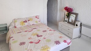 Un dormitorio con una cama, un tocador, un espejo y una mesita con flores.