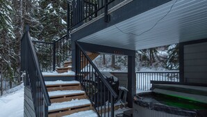 A wooden staircase leading to a deck area with a hot tub.