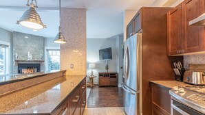 A modern kitchen with a central island, stainless steel appliances, and wooden cabinetry.