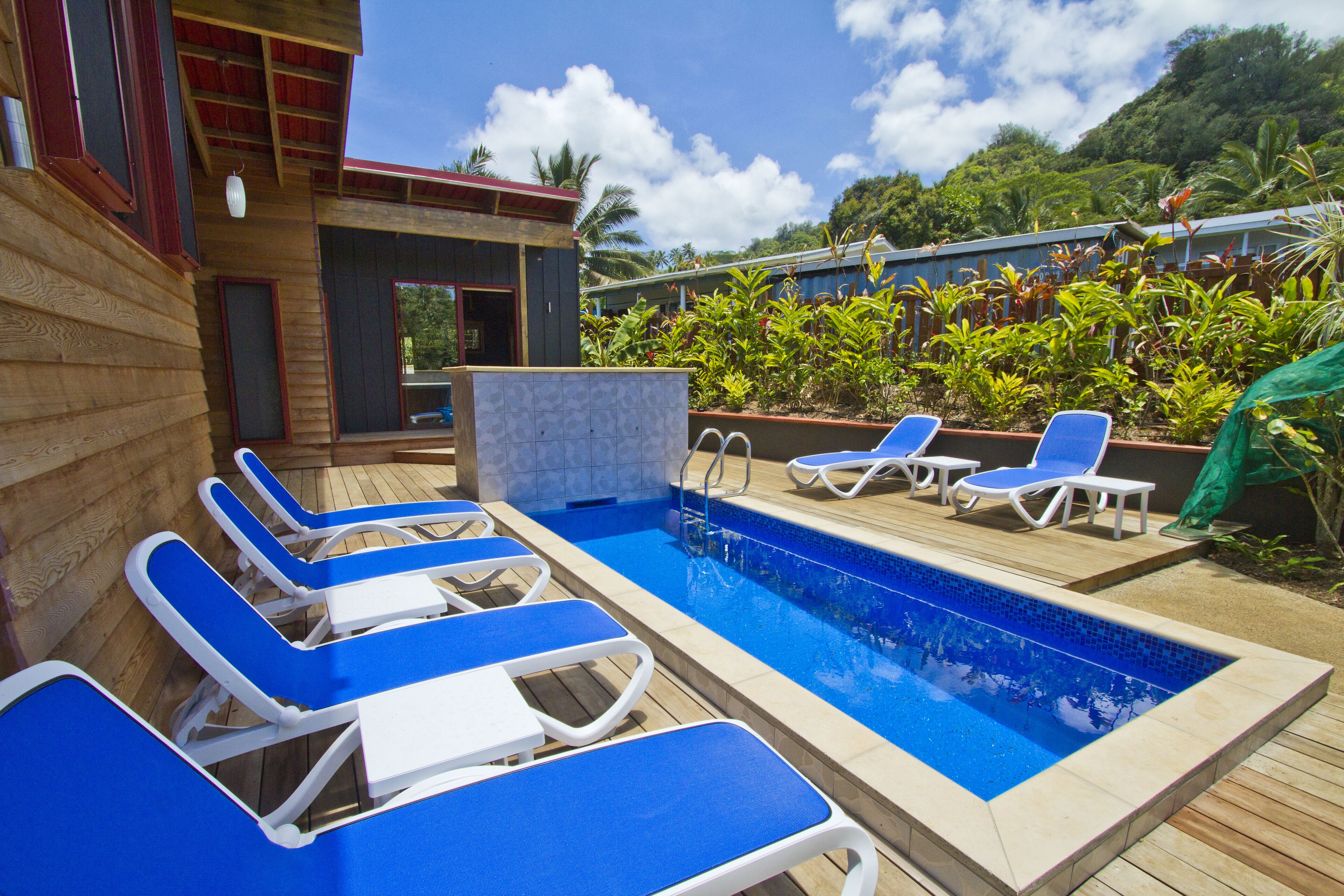 Uma área de piscina com cadeiras de sol azuis e uma piscina pequena.