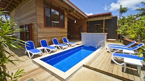 Ein Poolbereich mit Holzterrasse, Liegestühlen und einem Whirlpool.