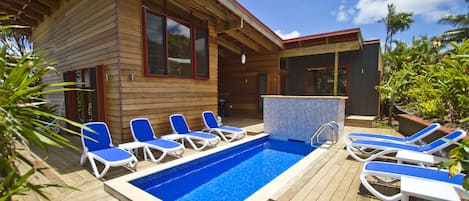 Relax by the pool surrounded by lounge chairs and a serene wooden deck.