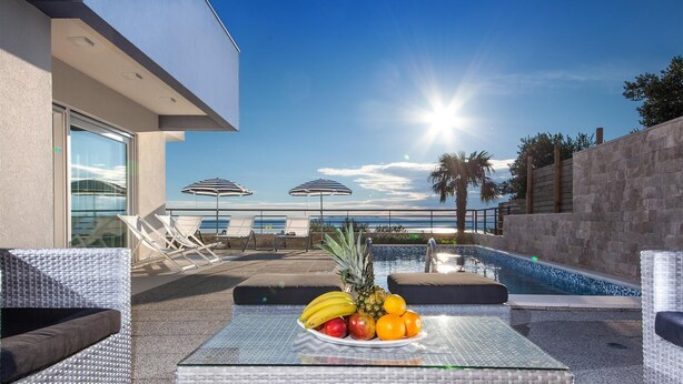 A poolside area with lounge chairs, a small pool, and a table with fruit. - Luxury Villa Blue Silk with Heated Pool (Makarska)