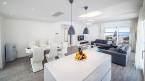 A modern living room with a sofa, a dining area with chairs, a kitchen island with fruit, and a balcony with a view. - Luxury Villa Blue Silk with Heated Pool (Makarska)