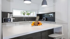 A modern kitchen with a white countertop, a microwave, a coffee maker, and a fruit bowl. - Luxury Villa Blue Silk with Heated Pool (Makarska)