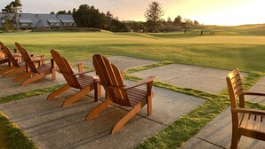 Un campo de golf con sillas de madera y un edificio al fondo.