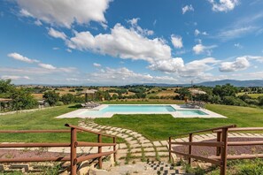 Piscina con vistas al campo, rodeada por una valla de madera y escalones que bajan al área de la piscina.