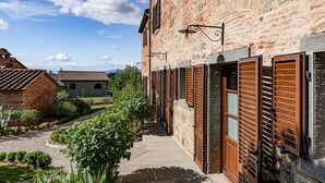 Un estrecho callejón con edificios de piedra, contraventanas de madera y un camino adoquinado.