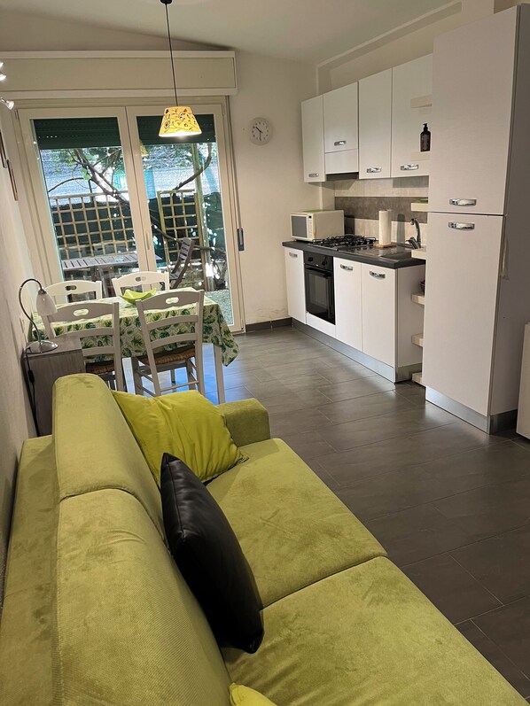 Una cocina moderna con armarios blancos, estufa y microondas. Hay una zona de comedor con una mesa y sillas.