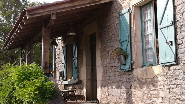 A rustic stone building with a wooden porch, green shutters, and a potted plant on the window sill. - Country cottage with swimming pool in the Quercy Regional Park (Larnagol)