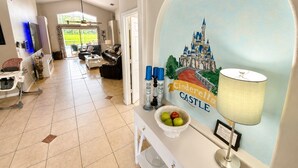 A living room with a large window, a dining area, and a wall with a castle painting.