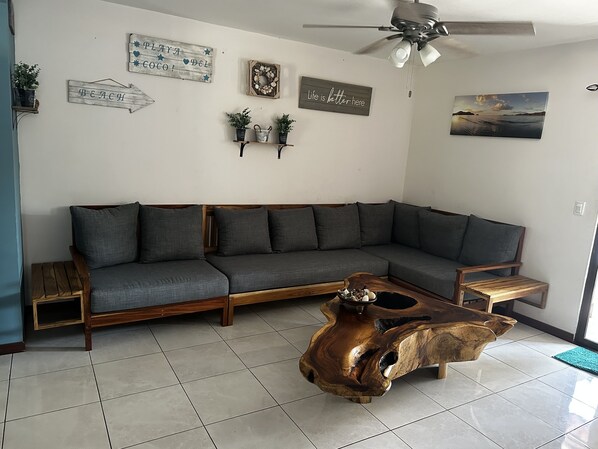 A living room with a sectional sofa, a wooden coffee table, and wall decorations including signs and a painting. - Newly Remodeled Condo MS #1 With 200MB Internet (Coco)
