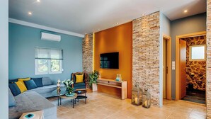 Una sala de estar moderna con un sofá gris, una mesa de centro, un televisor montado en una pared de ladrillo y una chimenea.