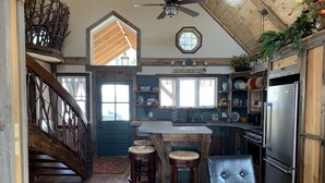 A rustic kitchen with a wooden staircase, a bar area, and a large refrigerator. - A soul soothing escape. Artistically built and lovingly maintained. (New Sharon)