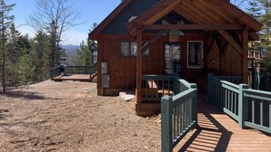 A wooden cabin with a covered porch, a small deck, and a view of the surrounding forest. - A soul soothing escape. Artistically built and lovingly maintained. (New Sharon)