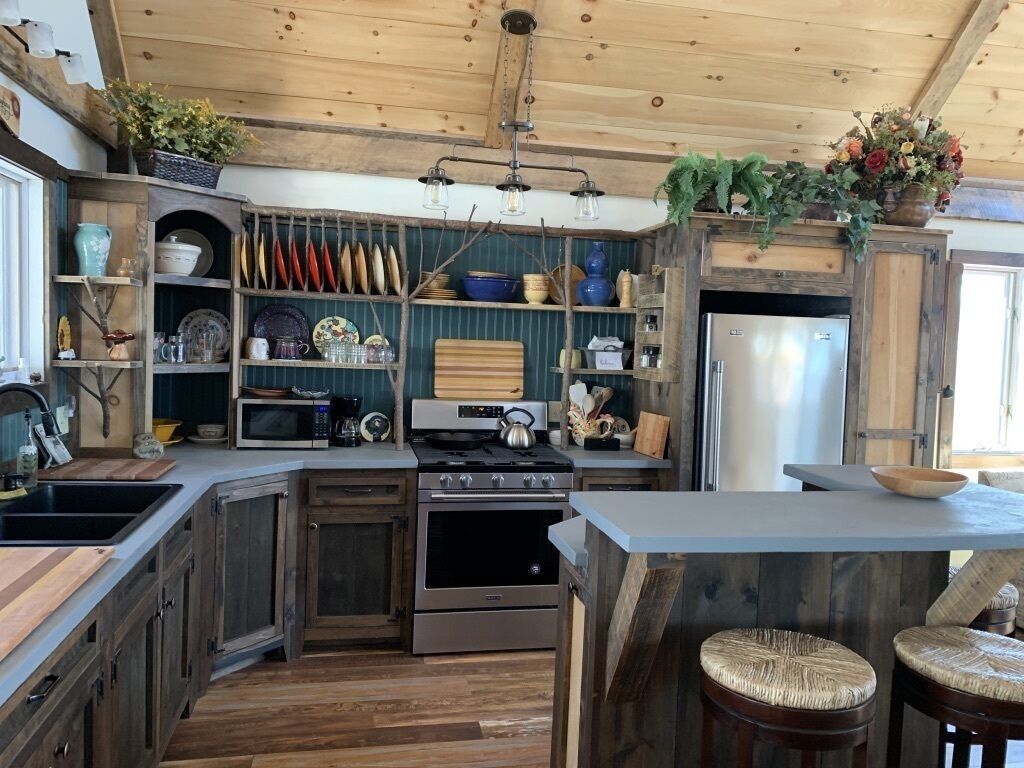 A rustic kitchen with wooden cabinets, a built-in stove, and a large island with stools.