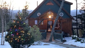 A wooden cabin with a porch, surrounded by snow and trees. - A soul soothing escape. Artistically built and lovingly maintained. (New Sharon)
