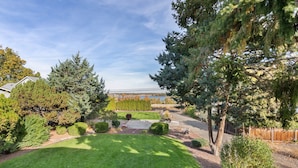 A well-maintained backyard with a lawn, various shrubs, and a wooden fence. - Lg House w beautiful River View 2 stories, 5bd3bth (Kennewick)