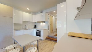 Una cocina moderna con armarios blancos, horno empotrado y cafetera.