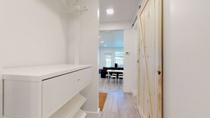 Un pasillo con un armario blanco, una puerta de madera y una vista parcial de un comedor con mesa y sillas.